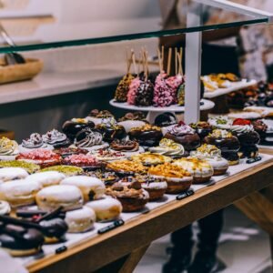 A tempting display of various donuts and pastries in a bakery. Ideal for food lovers and culinary enthusiasts.