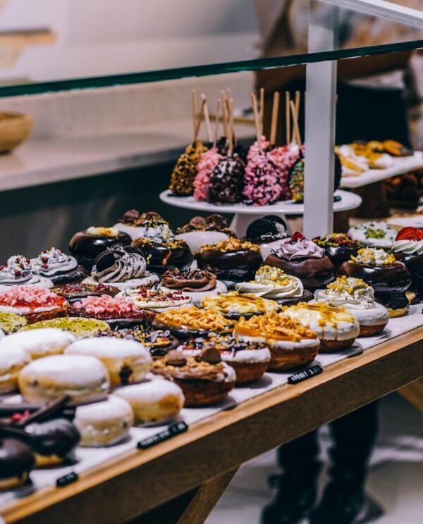 A tempting display of various donuts and pastries in a bakery. Ideal for food lovers and culinary enthusiasts.